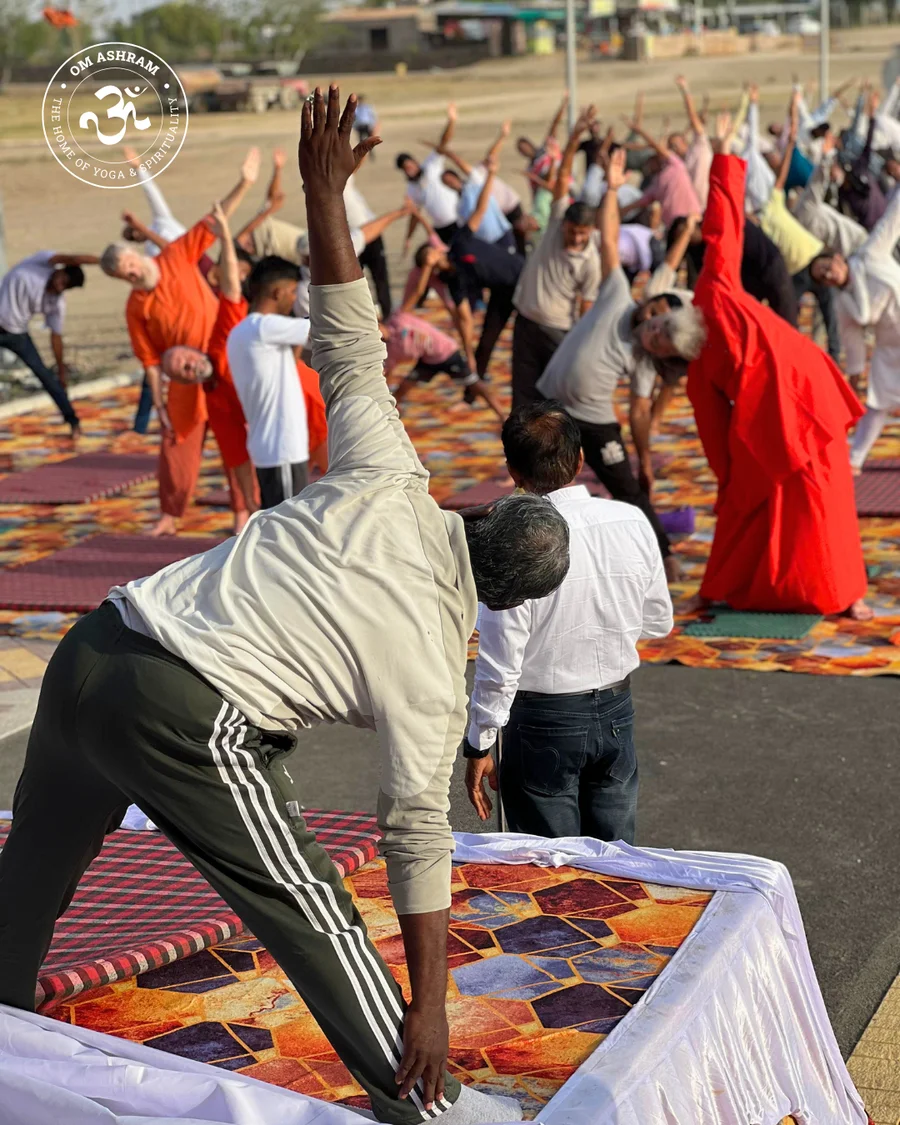 Expert demonstrators on a podium leading a large group practice at OM Ashram.